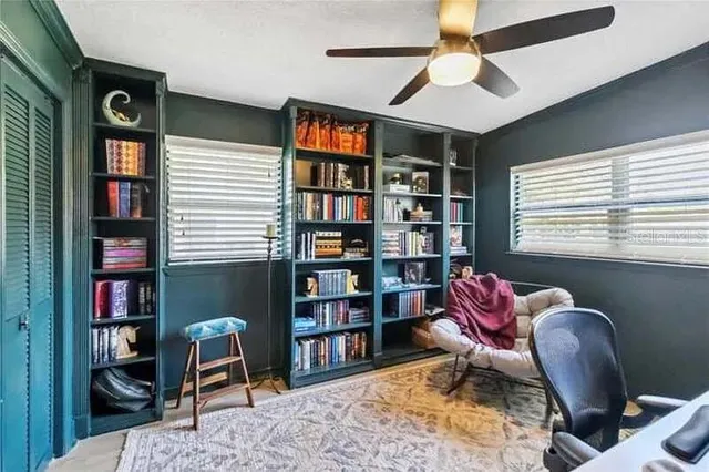 a livingroom with workspace bookshelf and a window