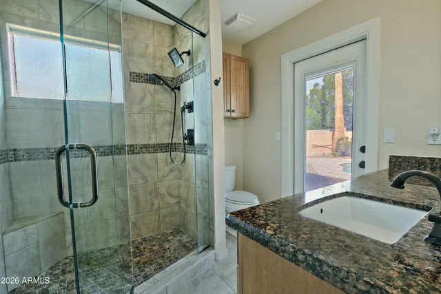 a bathroom with a granite countertop sink a mirror and a shower