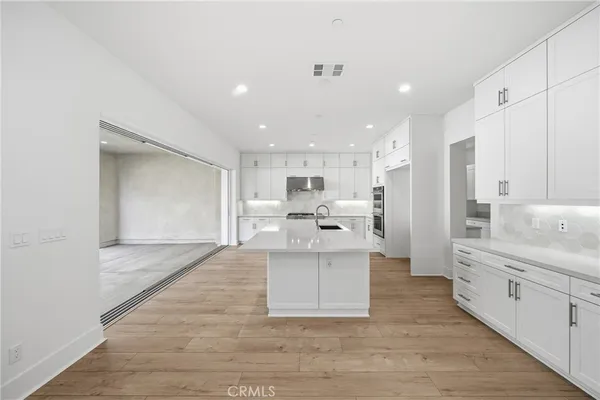 a large white kitchen with stainless steel appliances and white cabinets