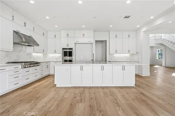 a kitchen with stainless steel appliances granite countertop a sink and cabinets with wooden floor