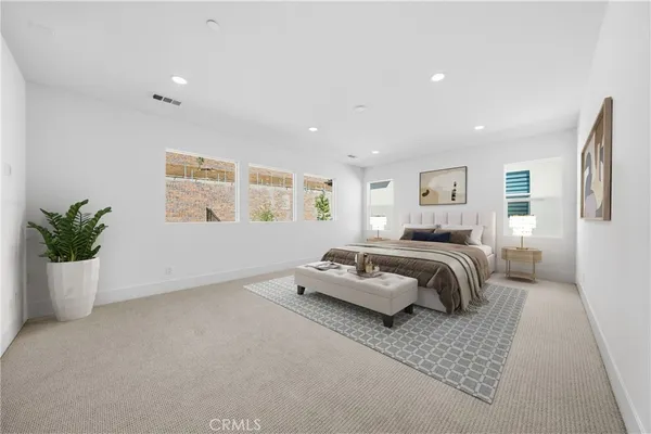 a spacious bedroom with a bed a couch and potted plant
