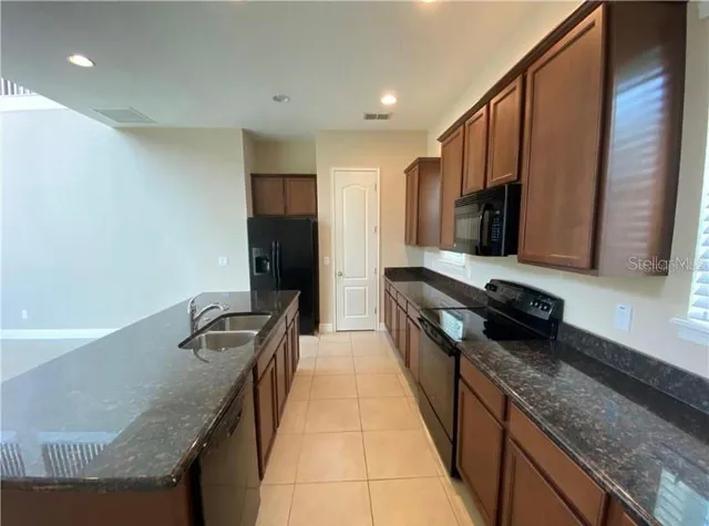 a kitchen with granite countertop a sink a stove top oven and wooden floor