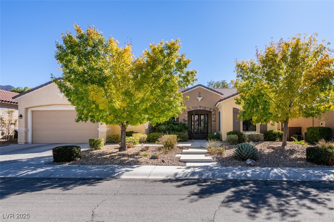 View of front of house with stucco siding, french doors, concrete driveway, and a garage