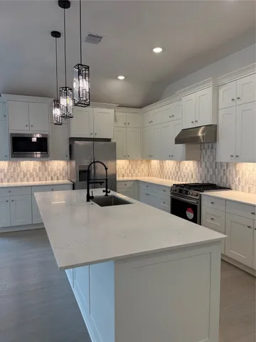 a kitchen with stainless steel appliances kitchen island granite countertop a sink a stove and a refrigerator