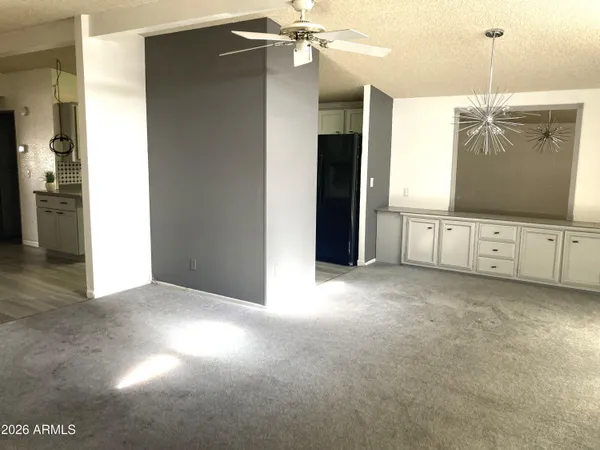 a view of an empty room with cabinet and kitchen view