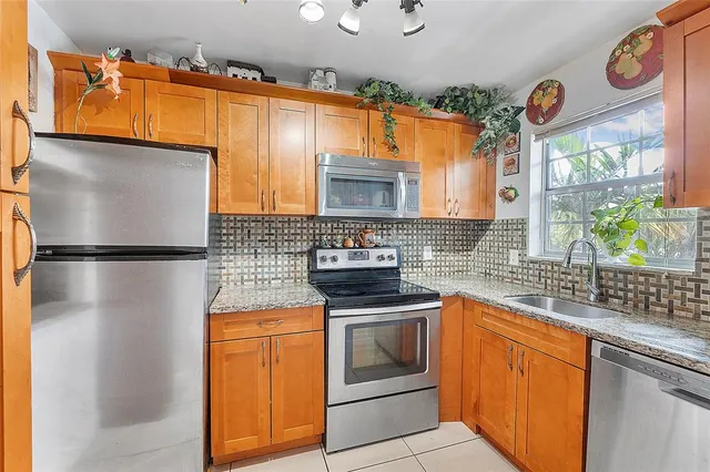 a kitchen with stainless steel appliances granite countertop a sink a stove and a refrigerator