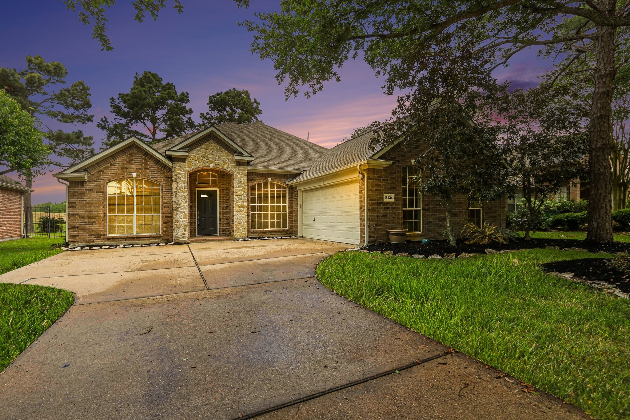 16434 Redcrest Drive Houston, TX 77095 - Photo 1 of 44 Charming brick home in the Guard -Gated section of Stone Gate with large windows, nestled among mature trees. Features a well-maintained lawn and a welcoming driveway, creating great curb appeal.