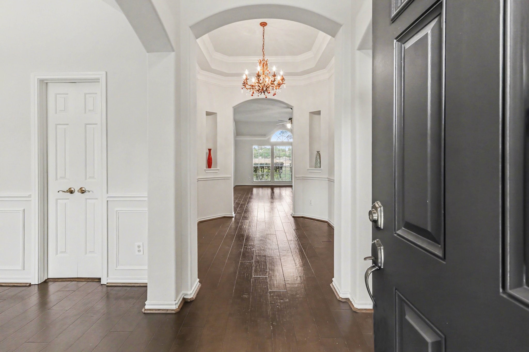 16434 Redcrest Drive Houston, TX 77095 - Photo 3 of 44 Inviting entryway with a private front door featuring decorative glass. Natural light fills the space through large windows, highlighting the elegant archways and dark hardwood floors. The adjoining rooms suggest an open, airy layout.
