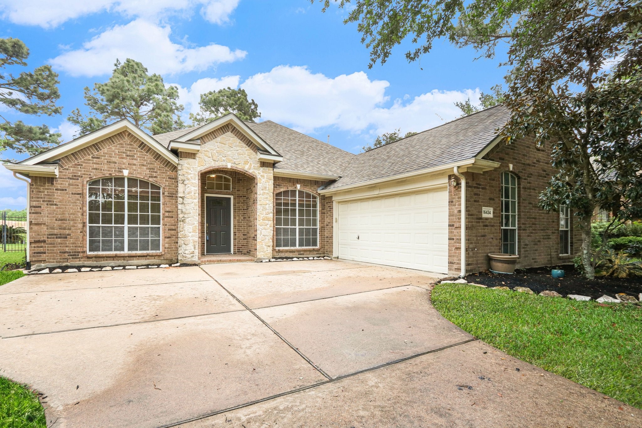 16434 Redcrest Drive Houston, TX 77095 - Photo 32 of 44 This is a charming single-story brick home with a well-maintained front yard and mature trees. It features a welcoming entryway and a two-car driveway, situated in a pleasant neighborhood setting.