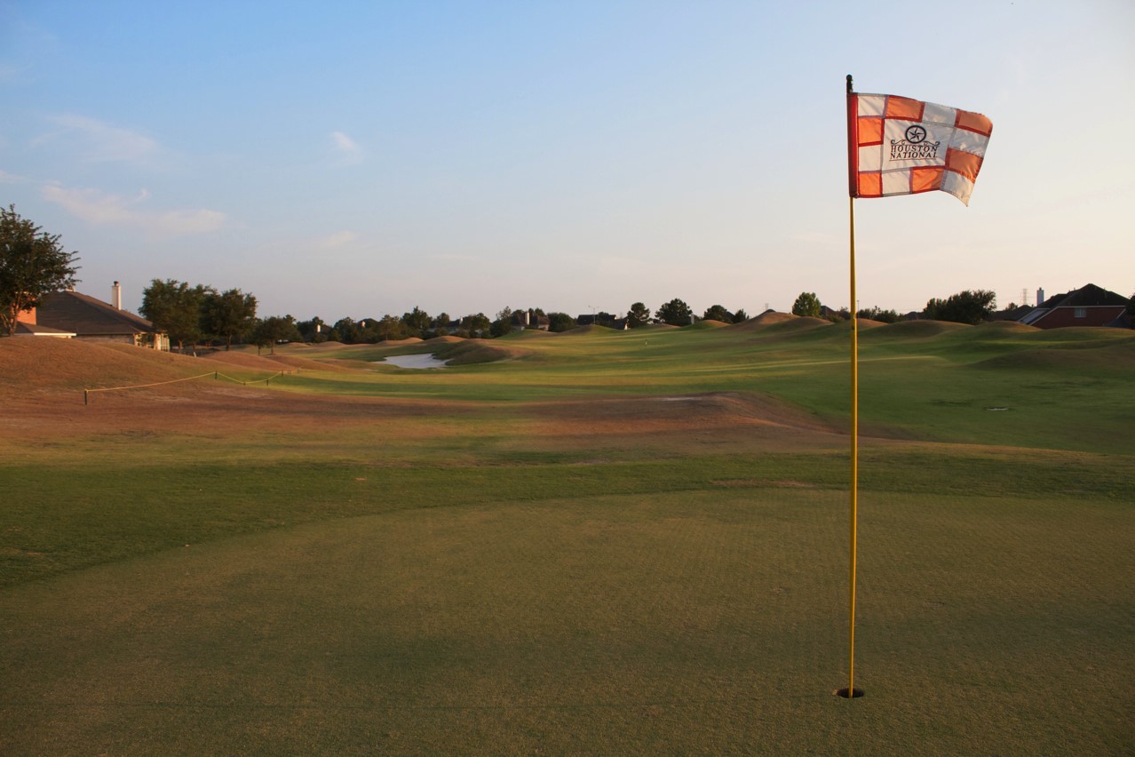 16434 Redcrest Drive Houston, TX 77095 - Photo 36 of 44 The photo showcases a scenic golf course view, featuring a well-maintained green and a flagpole, surrounded by gentle hills and nearby residential homes. Ideal for golf enthusiasts seeking a serene neighborhood.