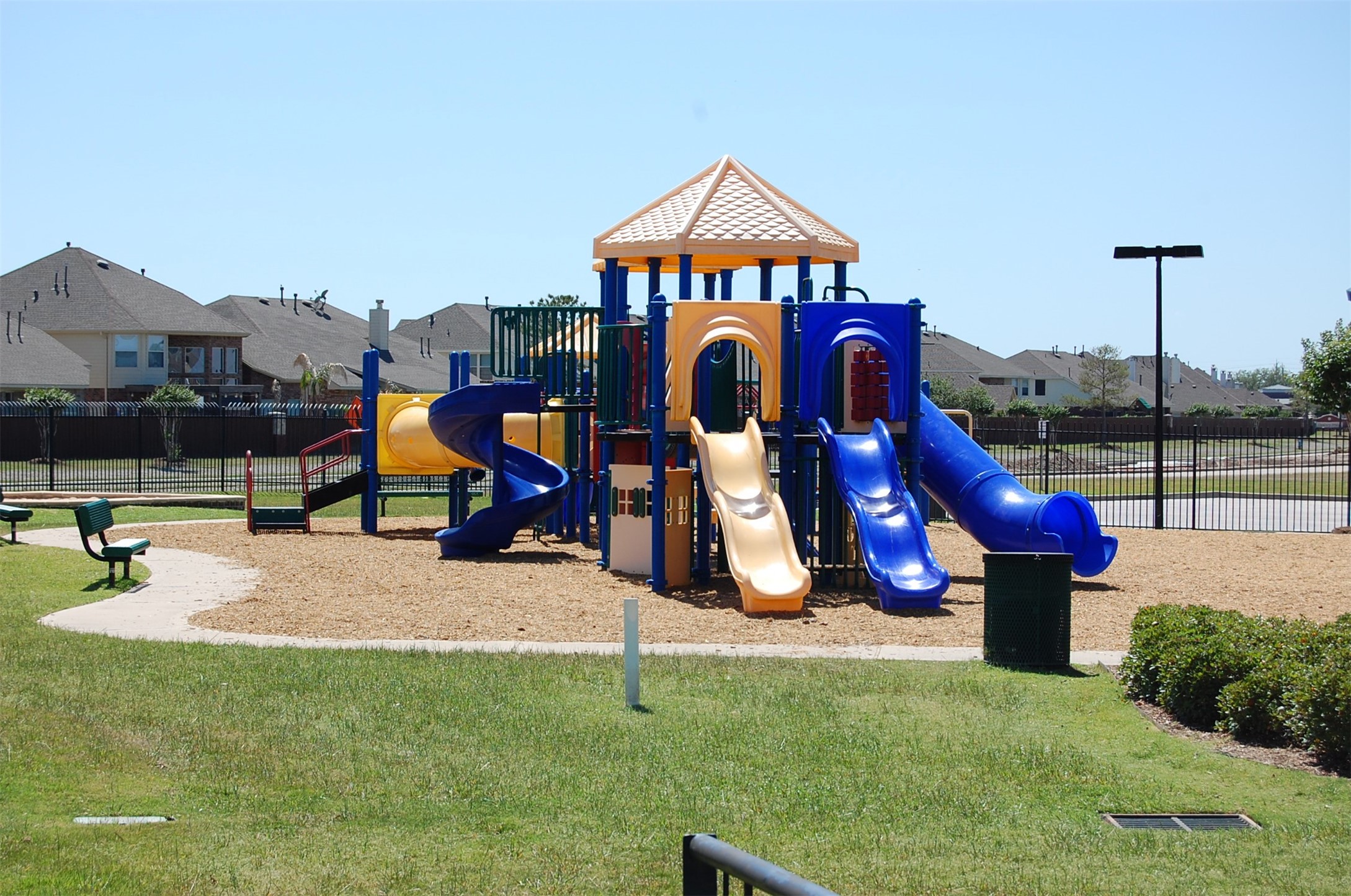 16434 Redcrest Drive Houston, TX 77095 - Photo 41 of 44 This photo shows a vibrant playground with slides and climbing structures, set in a well-maintained grassy area. It's perfect for families and located near a residential neighborhood.