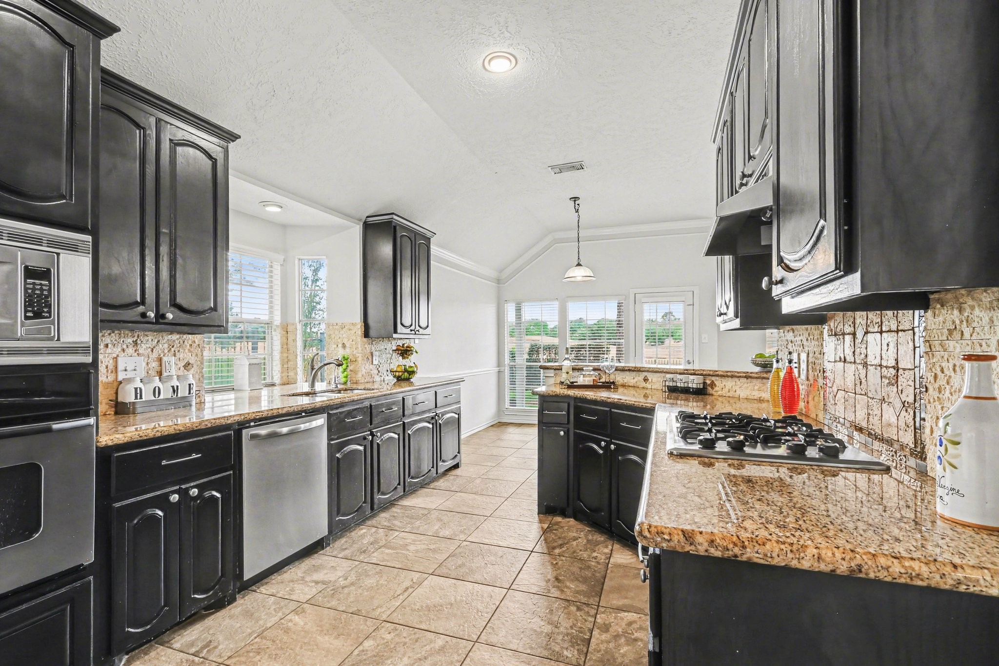 16434 Redcrest Drive Houston, TX 77095 - Photo 5 of 44 This kitchen features dark wood cabinetry, stainless steel appliances, and granite countertops. It has a spacious layout with tiled flooring and a cozy dining area by large windows, offering plenty of natural light.