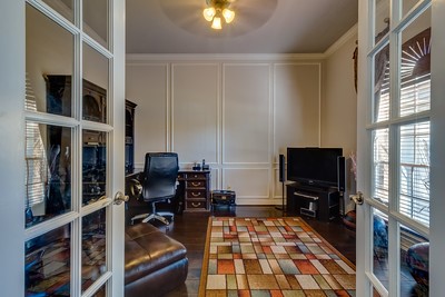16434 Redcrest Drive Houston, TX 77095 - Photo 8 of 44 This room features French doors, ample natural light, and warm wood flooring. It includes a work desk, comfortable seating, and a TV, creating a cozy and functional office or den space.