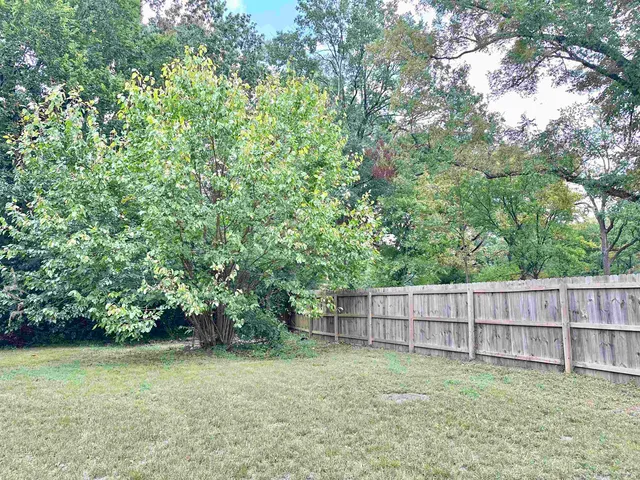 a view of a backyard with a fence and trees