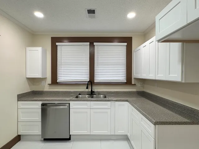 a kitchen with granite countertop white cabinets and a sink