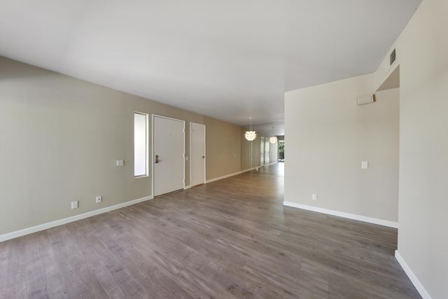 a view of an empty room with wooden floor and window
