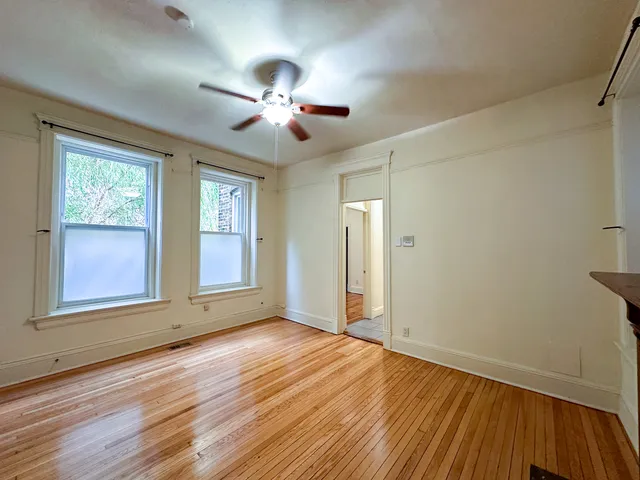 an empty room with wooden floor chandelier and windows