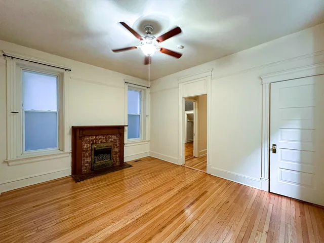 an empty room with wooden floor a ceiling fan and a window