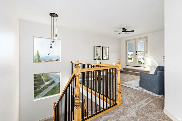 912 North Loafer Canyon Road Elk Ridge, UT 84651 - Photo 28 of 98 Staircase with wood balusters and black metal spindles, three square windows, three-light pendant fixture, carpeted landing, and double French doors