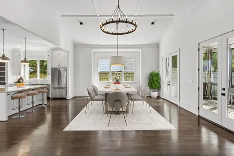 a view of an empty room with wooden floor and a kitchen