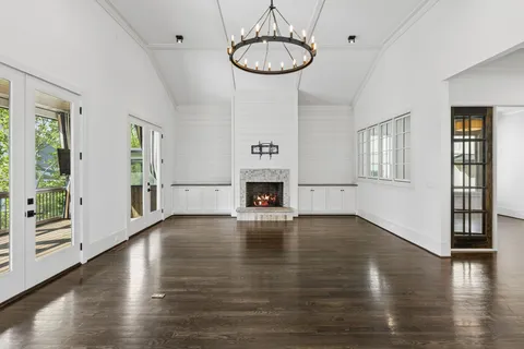 a view of an empty room and kitchen with a fireplace wooden floor