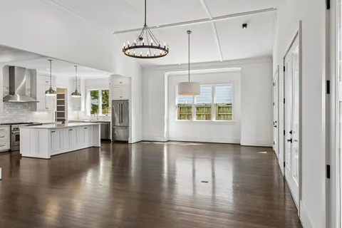 a view of an empty room and kitchen with a fireplace wooden floor