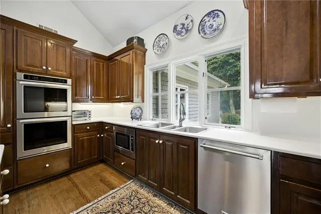 a kitchen with stainless steel appliances granite countertop a refrigerator a sink dishwasher and wooden cabinets with wooden floor