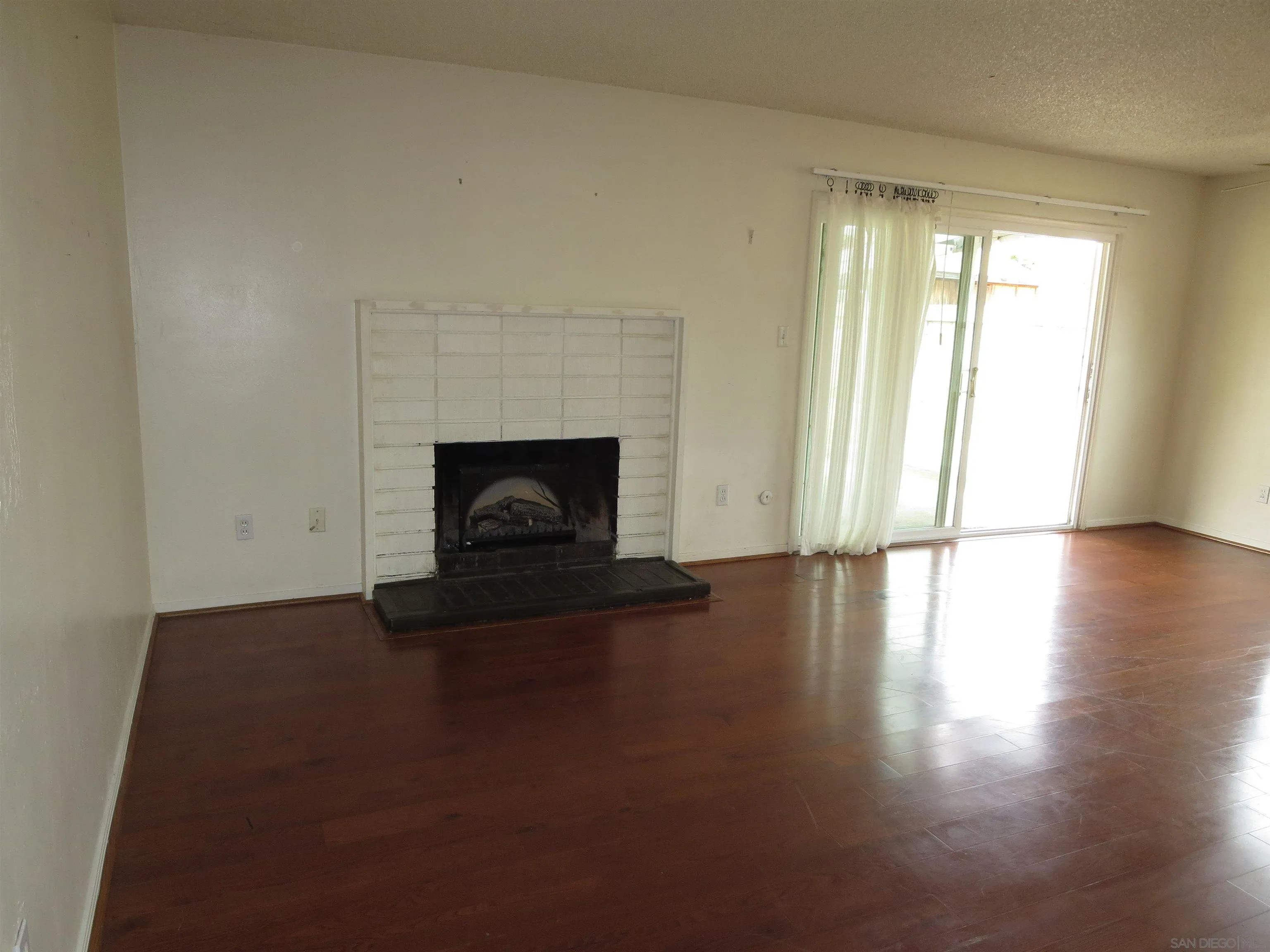 13516 Frame Road Poway, CA 92064 - Photo 16 of 39 a view of an empty room with wooden floor fireplace and a window
