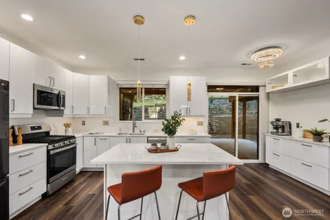 a kitchen with stainless steel appliances granite countertop a stove top oven a sink dishwasher a dining table and chairs with wooden floor