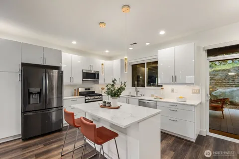 a kitchen with a refrigerator a stove a sink and white cabinets with wooden floor