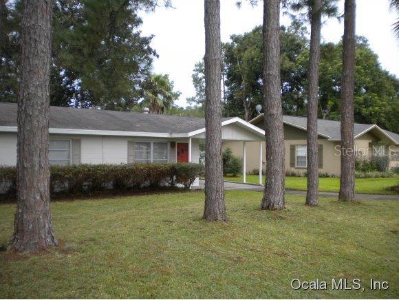 a view of a house with a yard and a large tree