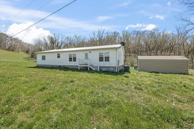 a view of a house with a backyard and trees