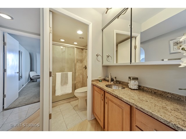 300 North State Street, Unit 5518 Chicago, IL 60654 - Photo 13 of 16 a bathroom with a granite countertop sink a toilet and shower