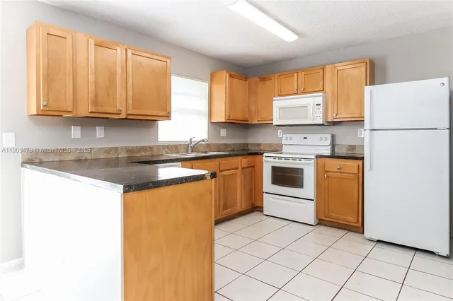 a kitchen with a sink a stove top oven and white stainless steel appliances