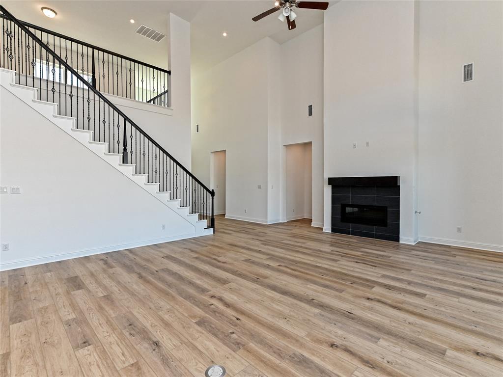 270 Prairie Clover Drive Dripping Springs, TX 78620 - Photo 8 of 28 Unfurnished living room featuring a tile fireplace, light wood finished floors, a high ceiling, a ceiling fan, and recessed lighting