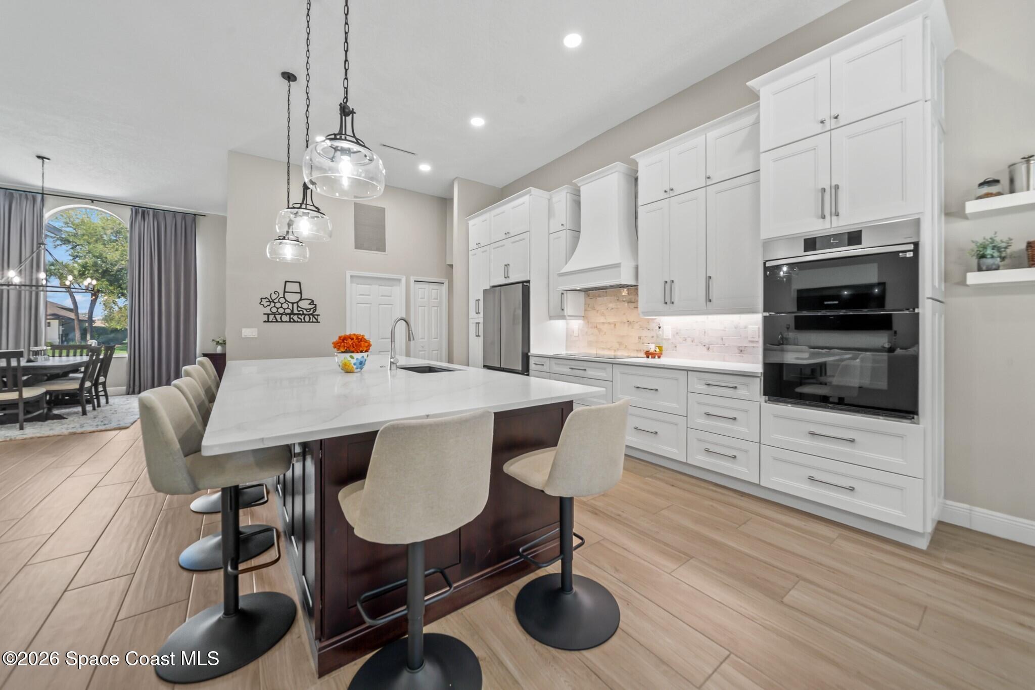 697 Spring Lake Drive Melbourne, FL 32940 - Photo 13 of 45 a kitchen with stainless steel appliances kitchen island granite countertop a sink a stove a dining table and chairs with wooden floor