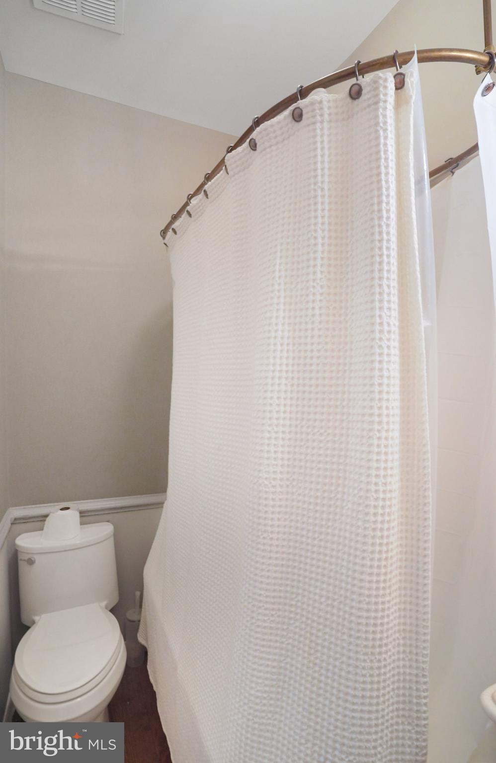 7153 Main Street Clifton, VA 20124 - Photo 45 of 77 a white toilet sitting next to a shower curtain