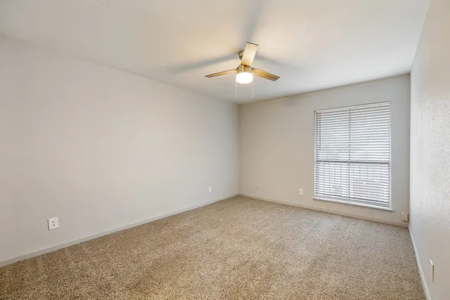 an empty room with windows and ceiling fan