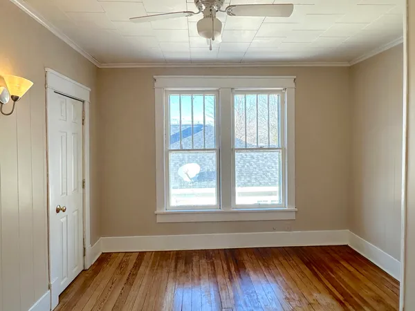 a view of an empty room with wooden floor and a window