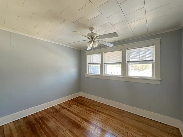 an empty room with wooden floor and windows