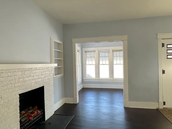 a living room with wooden floor and a fireplace