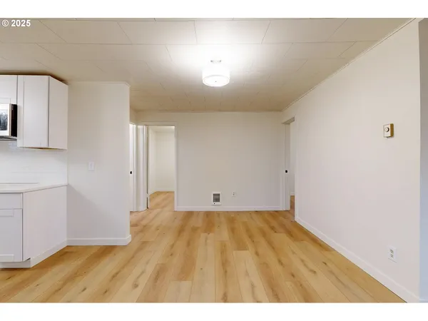a view of an empty room with window and wooden floor