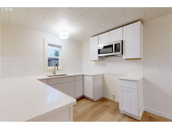a kitchen with white cabinets a sink and a oven with wooden floor