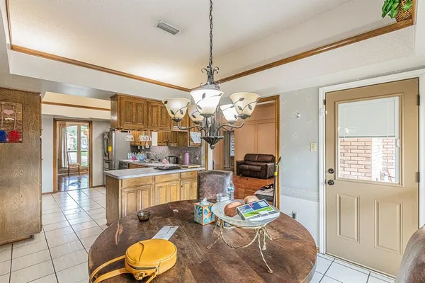 a dining room with wooden floor a chandelier a wooden table and chairs