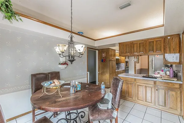 a dining room filled chandelier and kitchen view