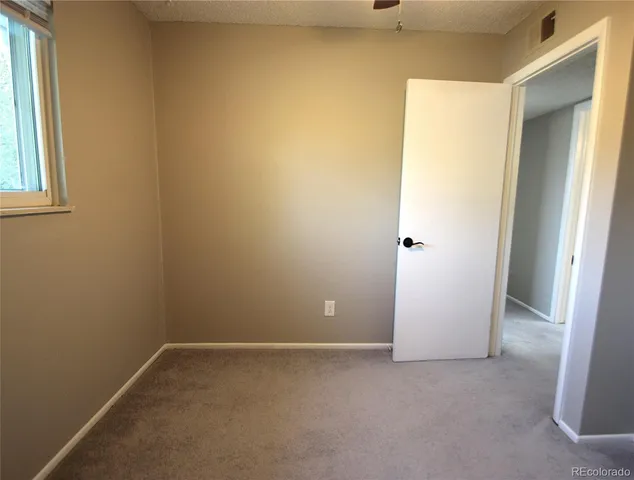 an empty room with a window and a fan