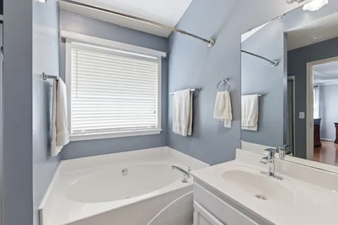a bathroom with a tub sink and mirror