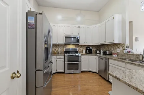 a kitchen with stainless steel appliances granite countertop a stove a sink and a refrigerator