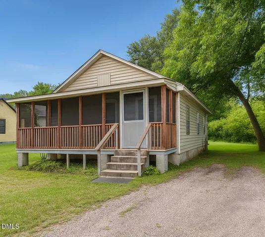 a view of a house with a yard and large trees