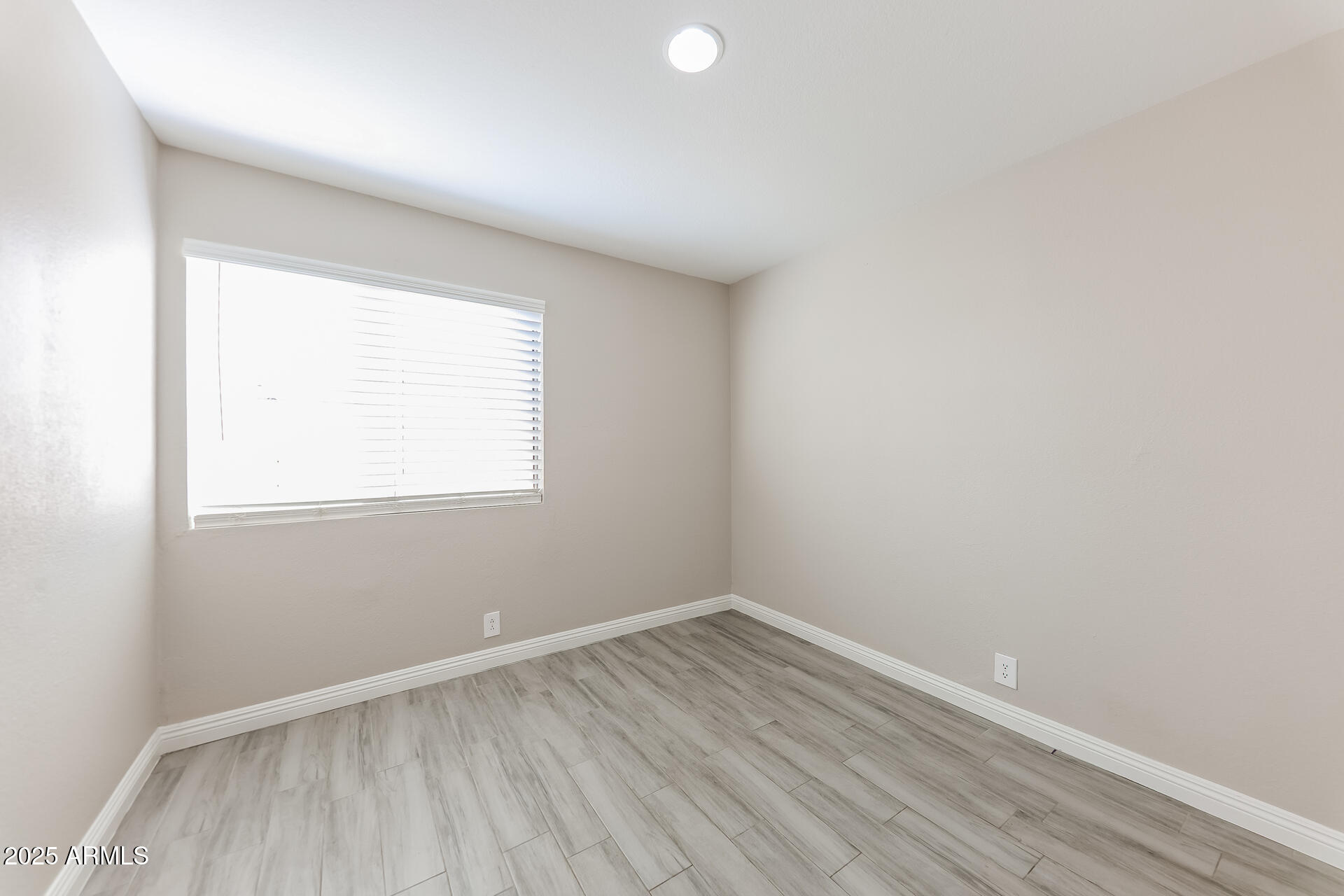 8833 West Monte Vista Road Phoenix, AZ 85037 - Photo 12 of 21 an empty room with wooden floor and windows